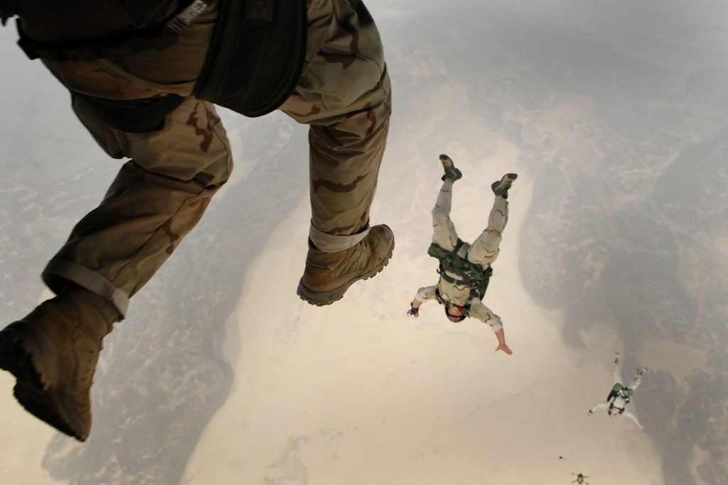 Military skydivers leap from the plane, one by one