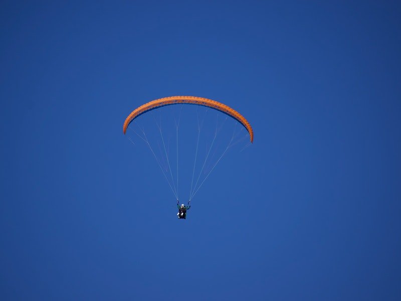 Gliding down on a parachute behind blue sky